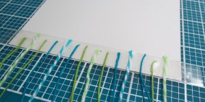 Baby Shower Scrapbook Ideas: using the grid to mark off the spacing of the twine.
