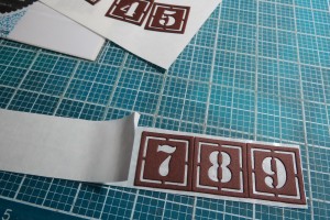Great Expectations: Stencil Number Dies being placed on Stick It! Adhesive 