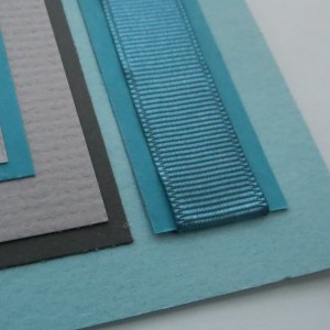 Ribbon ends are tucked to the back page by a slit along the tile edge.